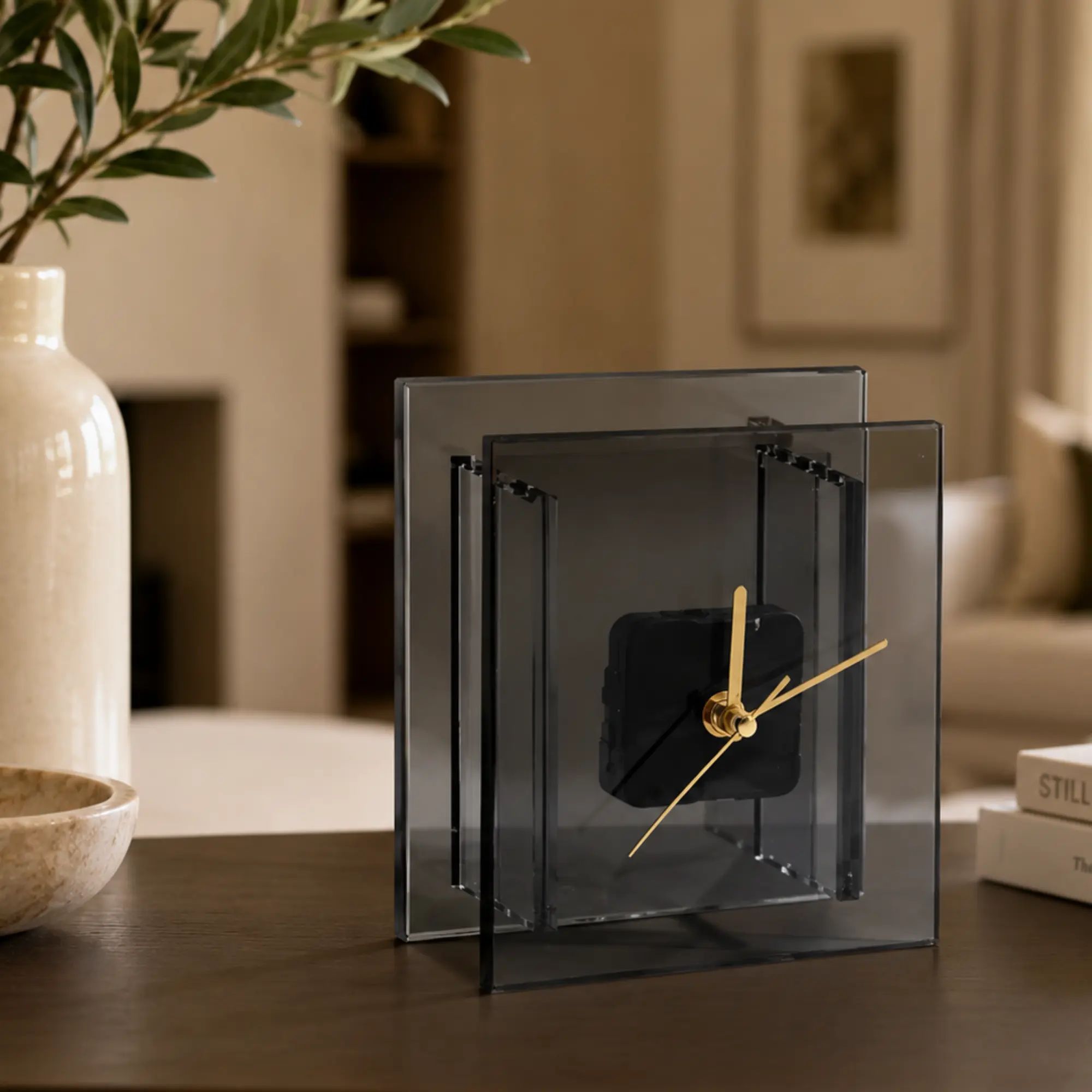 Tischuhr - mit Goldzeiger - Puristische Designuhr – Quadratische Rauchglas-Acryl Dekouhr mit goldenen Zeigern Noctis Aurum aufgestellt im Interieur